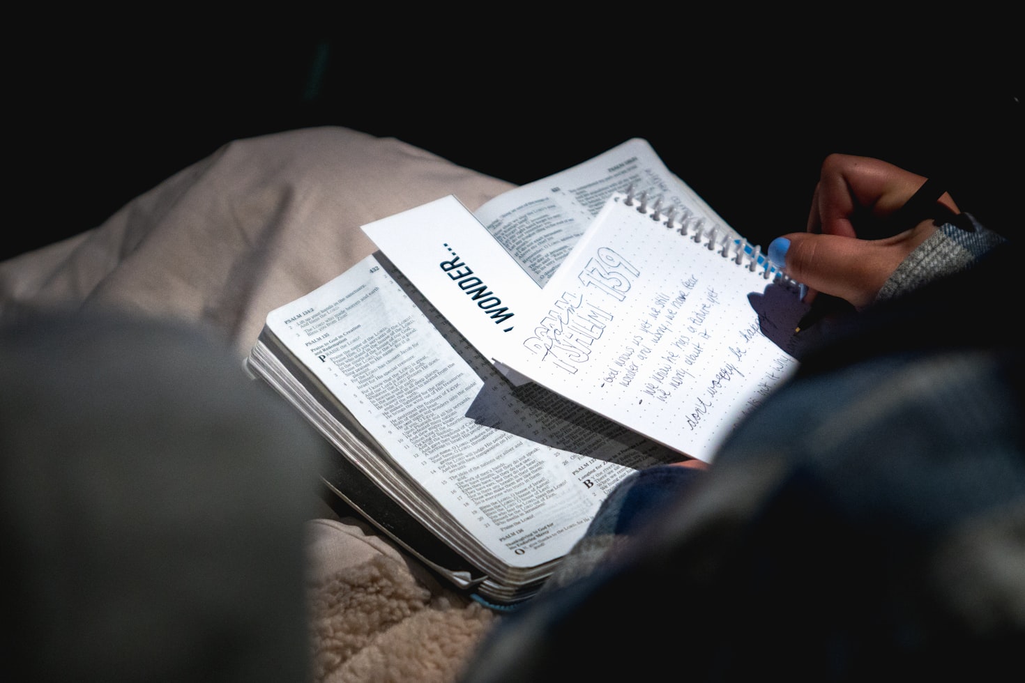 A person writing a prayer request beside an open Bible